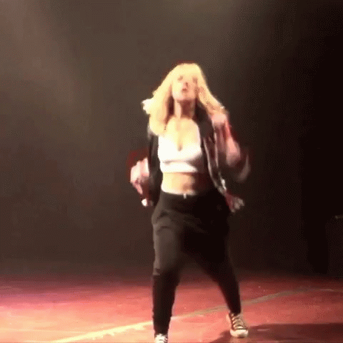 A Woman In A Crop Top And Black Pants Dances On A Stage GIF