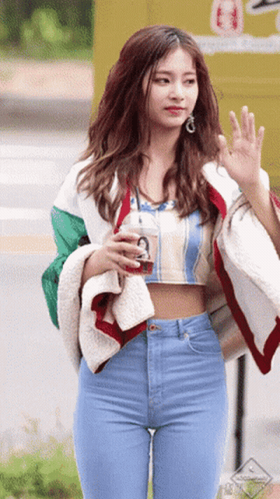 A Woman In A Crop Top And Jeans Is Holding A Drink GIF