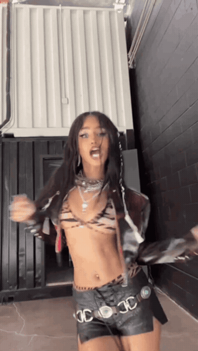 A Woman In A Crop Top And Leather Shorts Is Dancing . GIF