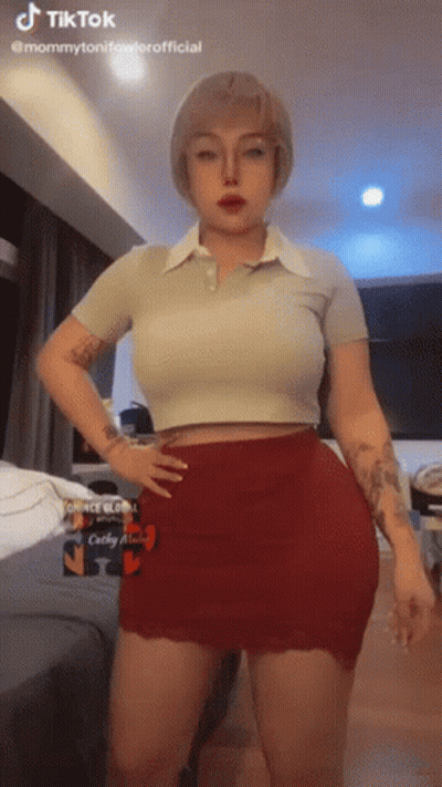 A Woman In A Crop Top And Red Skirt Is Standing With Her Hands On Her Hips . GIF