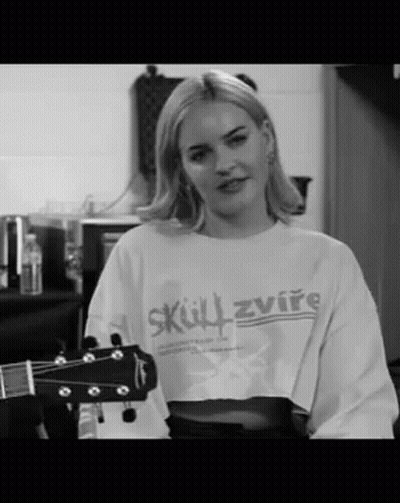 A Woman In A Crop Top Is Holding A Guitar . GIF
