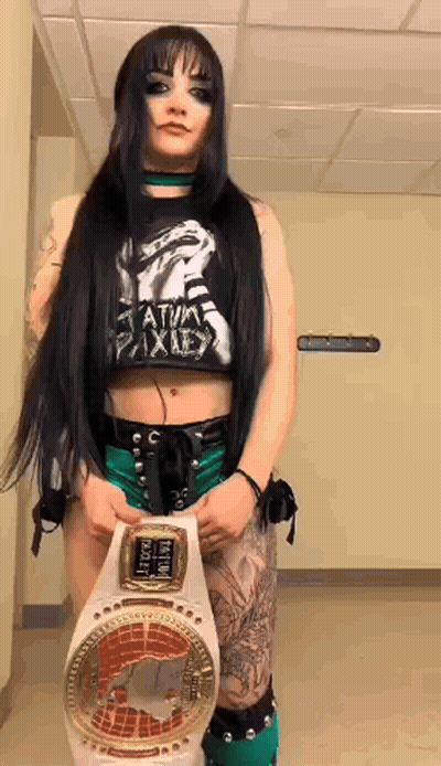 A Woman In A Crop Top Is Holding A Wrestling Belt . GIF
