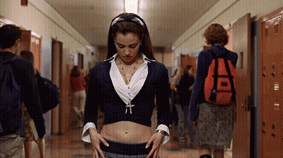 A Woman In A Crop Top Stands In A Hallway With Lockers GIF