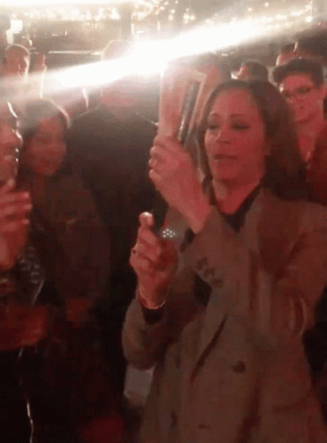 A Woman In A Crowd Holds A Bottle Of Budweiser GIF