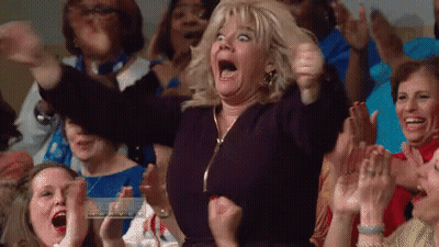 A Woman In A Crowd Of People Is Making A Funny Face . GIF