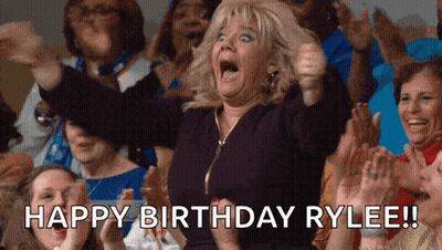 A Woman In A Crowd Says Happy Birthday Rylee In Front Of Her GIF