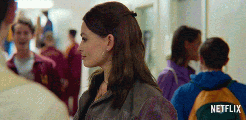 A Woman In A Crowded Hallway With A Netflix Logo In The Corner GIF