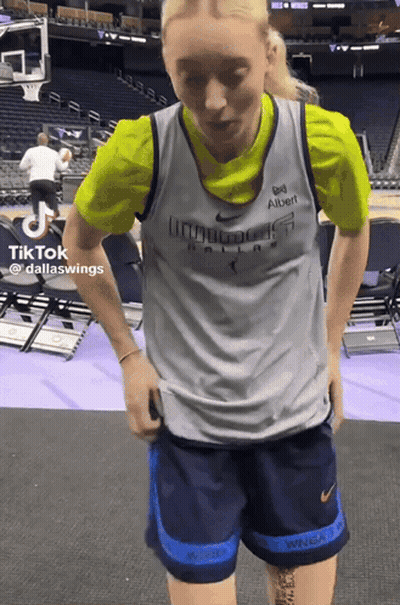 A Woman In A Dallas Wings Jersey Is Standing In A Stadium GIF