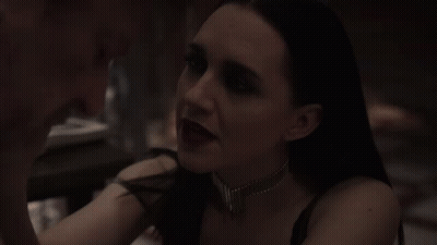 A Woman In A Dark Room Is Looking At Another Woman . GIF