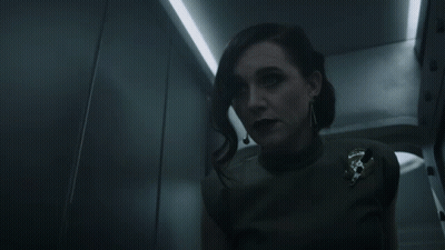 A Woman In A Dark Room With A Badge That Says U.s. Army On It GIF