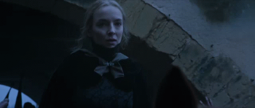 A Woman In A Dark Room With A Brick Wall In The Background GIF