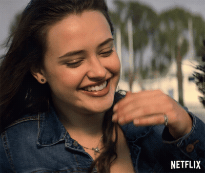 A Woman In A Denim Jacket Is Smiling With A Netflix Logo In The Background GIF