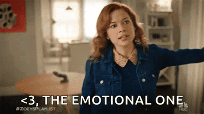 A Woman In A Denim Jacket Is Standing In A Living Room With Her Arms Outstretched And Says The Emotional One . GIF