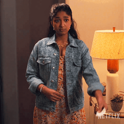 A Woman In A Denim Jacket Is Standing In Front Of A Lamp With Netflix Written On The Bottom GIF