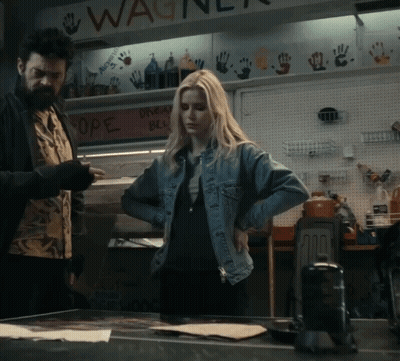 A Woman In A Denim Jacket Is Standing In Front Of A Sign That Says Wagner GIF