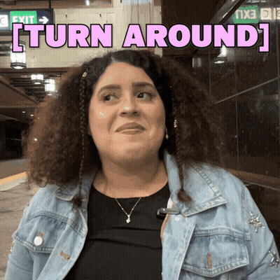 A Woman In A Denim Jacket With The Words Turn Around Behind Her GIF