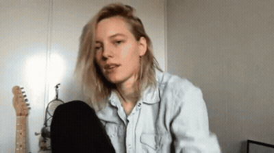 A Woman In A Denim Shirt Is Sitting In Front Of A Microphone In A Room . GIF