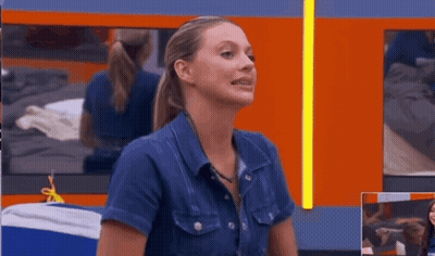 A Woman In A Denim Shirt Is Sitting In Front Of A Mirror GIF