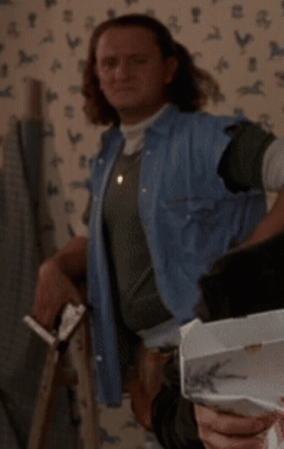 A Woman In A Denim Vest Is Standing In Front Of A Wall With Chickens On It GIF