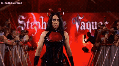 A Woman In A Devil Costume Is Walking In Front Of A Crowd . GIF