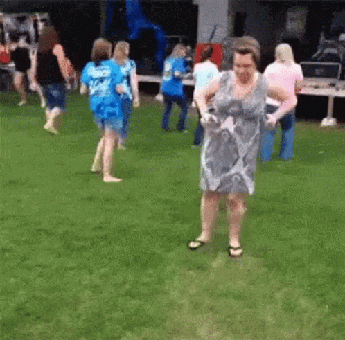 A Woman In A Dress Is Dancing In A Grassy Field . GIF