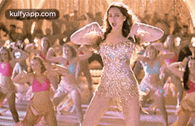 A Woman In A Dress Is Dancing In Front Of A Group Of Dancers . GIF