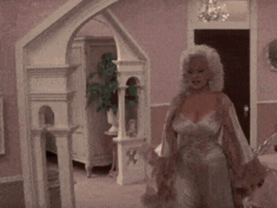 A Woman In A Dress Is Standing In A Room GIF