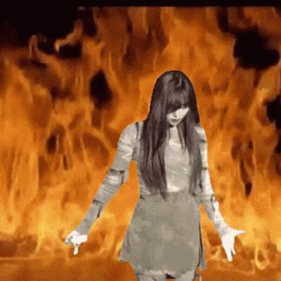 A Woman In A Dress Is Standing In Front Of A Fire GIF