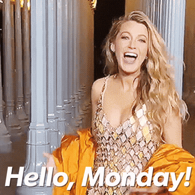 A Woman In A Dress Is Standing In Front Of Columns And Says Hello Monday GIF