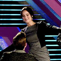 A Woman In A Dress Is Standing Next To A Man On A Set Of Stairs GIF