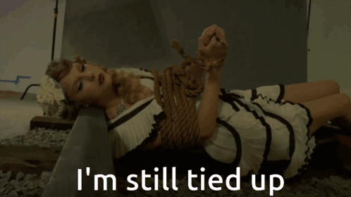 A Woman In A Dress Is Tied Up And Says I 'M Still Tied Up Below Her GIF