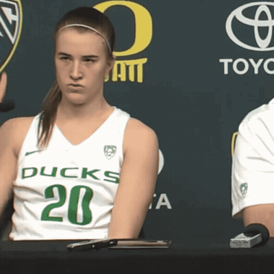 A Woman In A Ducks Jersey Sits At A Desk GIF
