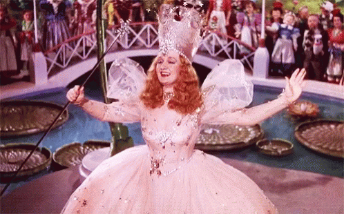 A Woman In A Fairy Costume Is Holding A Wand In Her Hand . GIF