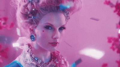 A Woman In A Fancy Dress Costume With A Heart On Her Cheek Looks At The Camera GIF