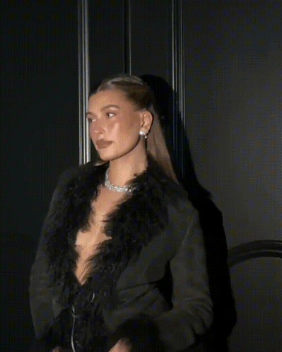 A Woman In A Feathered Coat Looks Up At The Sky GIF