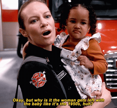 A Woman In A Fire Department Uniform Is Holding A Small Child GIF