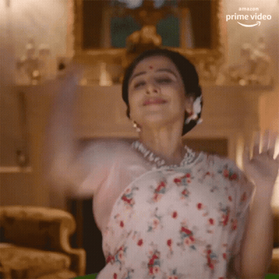 A Woman In A Floral Dress Is Dancing In A Living Room With The Amazon Prime Video Logo Visible GIF