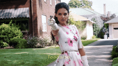 A Woman In A Floral Dress Is Pointing A Gun At The Camera With The Word Toodalo On The Bottom Of The Image GIF
