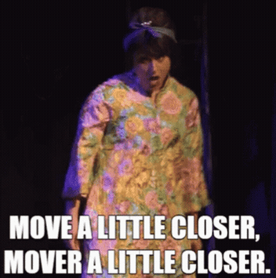 A Woman In A Floral Dress Is Saying Move A Little Closer , Mover A Little Closer . GIF
