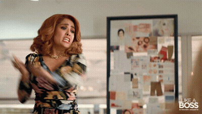 A Woman In A Floral Dress Is Standing In Front Of A Framed Picture That Says Like A Boss GIF