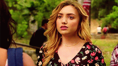 A Woman In A Floral Dress Is Standing Next To A Man In A Plaid Shirt In A Park . GIF