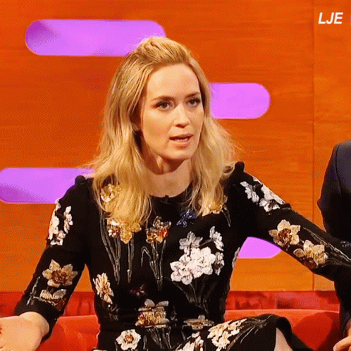 A Woman In A Floral Dress Sits On A Red Couch In Front Of A Screen That Says Lje GIF