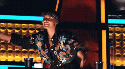 A Woman In A Floral Jacket Is Sitting In A Chair With Her Arms Outstretched .. GIF