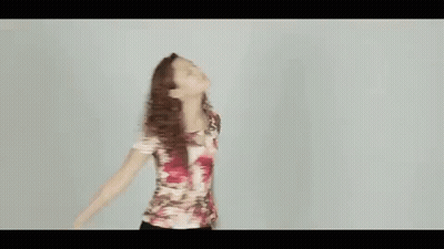 A Woman In A Floral Shirt Is Dancing With Her Arms Outstretched . GIF