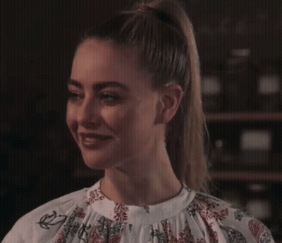 A Woman In A Floral Shirt Is Smiling And Looking At The Camera GIF