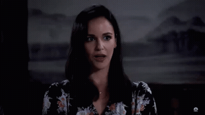 A Woman In A Floral Shirt Is Standing In Front Of A Large H . GIF