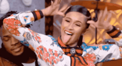 A Woman In A Floral Shirt Is Sticking Her Tongue Out . GIF