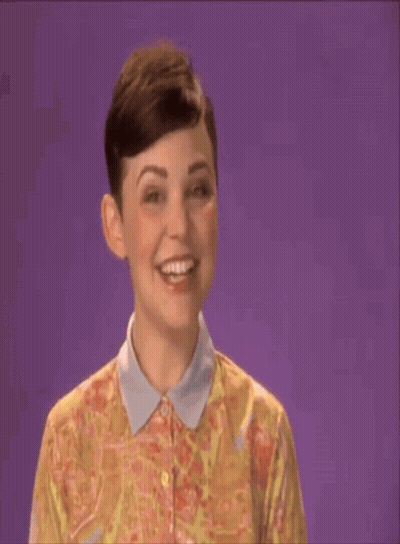 A Woman In A Floral Shirt Says Shana Tova On A Purple Background GIF