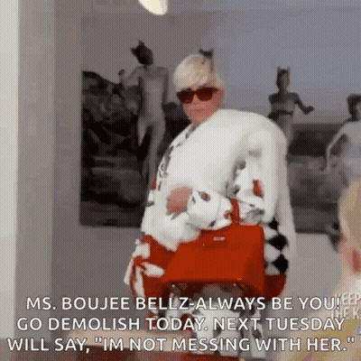 A Woman In A Fur Coat And Sunglasses Is Holding A Red Purse And Talking To Another Woman . GIF