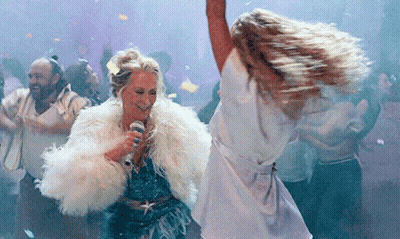 A Woman In A Fur Coat Is Singing Into A Microphone While Dancing GIF
